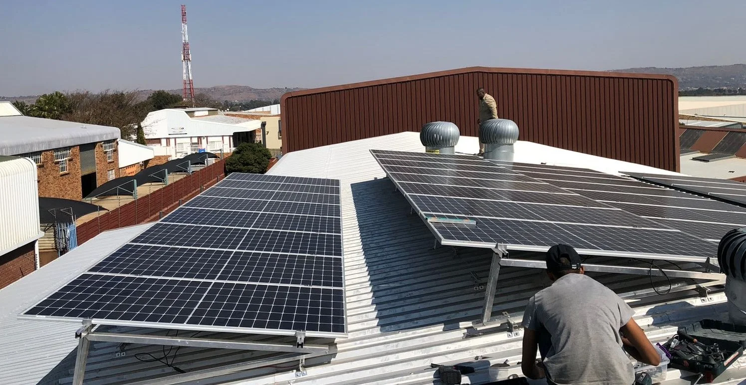 Technicians working on a large commercial rooftop solar array